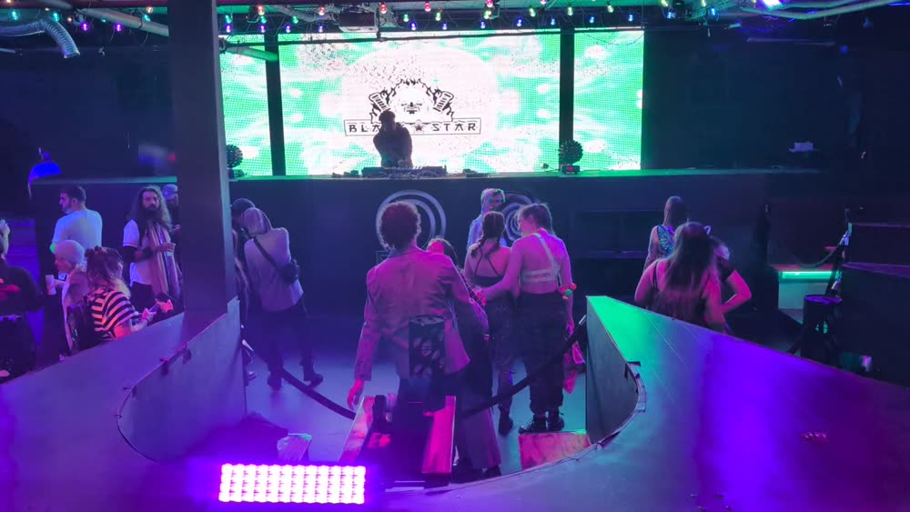 Seattle club dance floor with a green LED wall behind the DJ